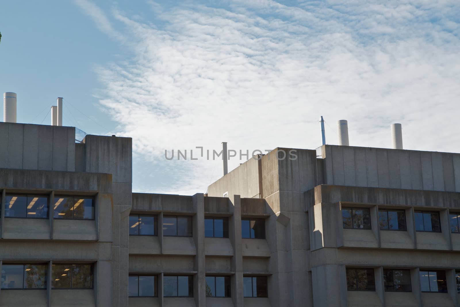 Weather worn moderneristic looking building against blue sky with white cloudscape