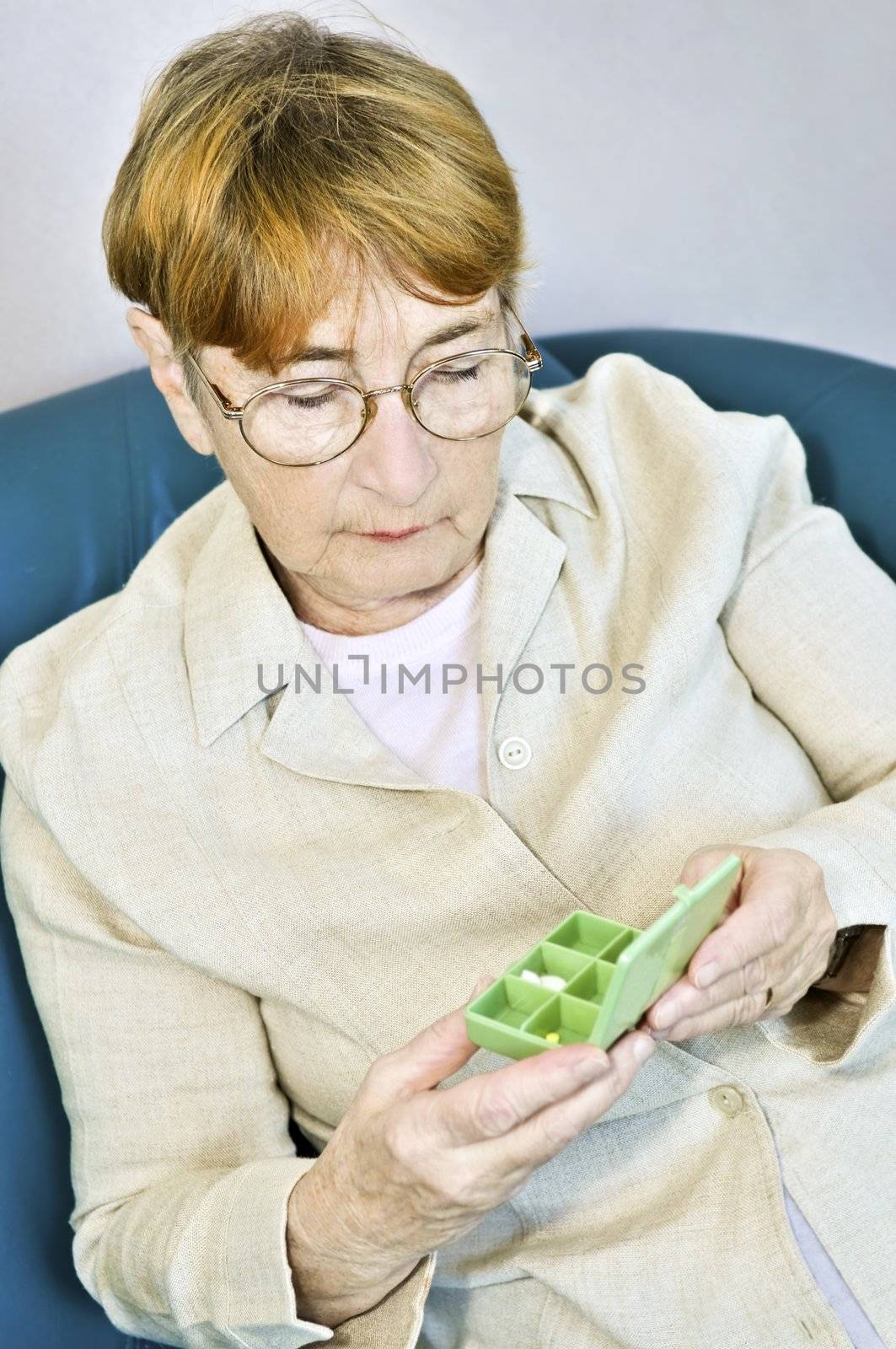 Elderly woman holding pill box with medication