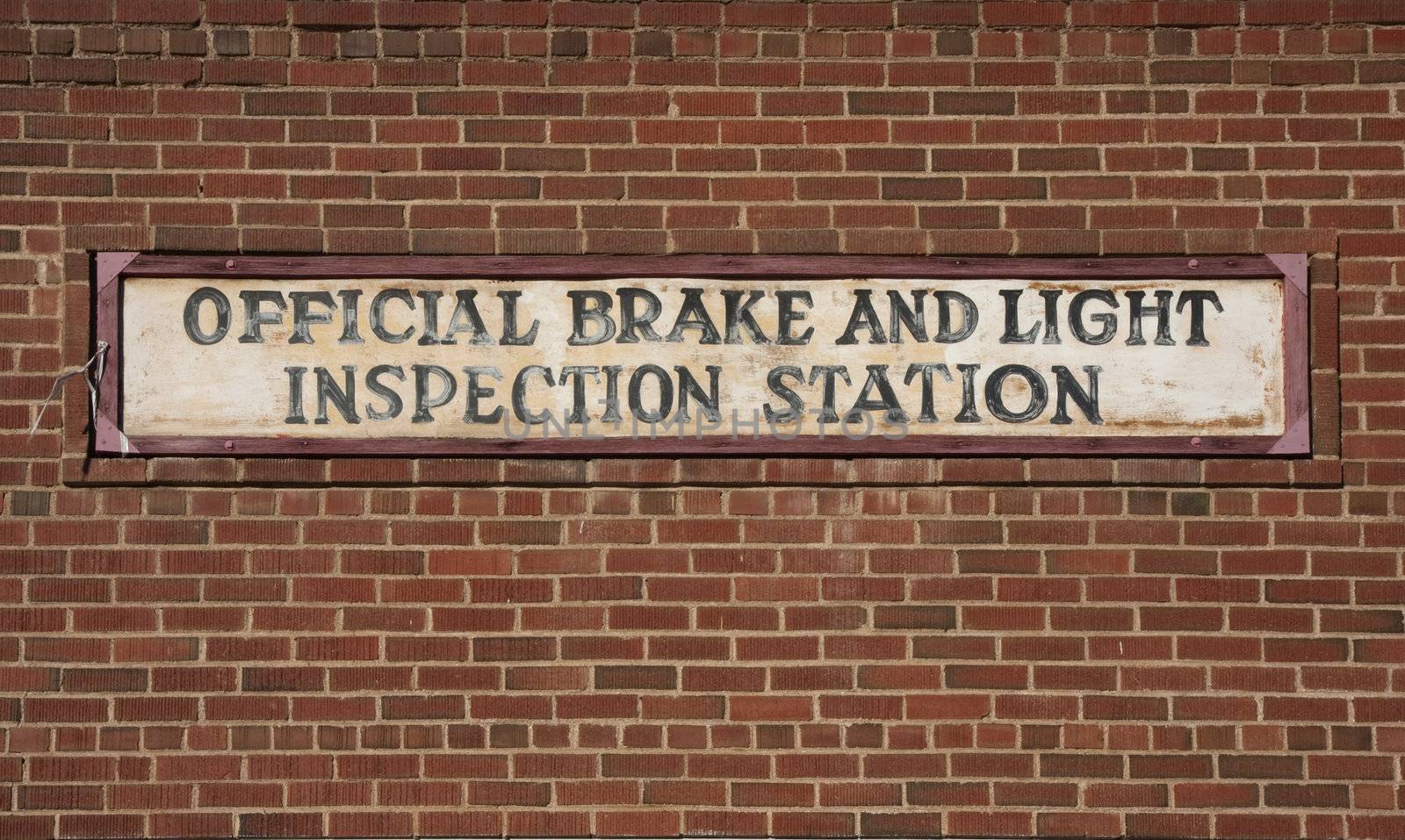 vintage brake and light inspection sign against red brick wall from an old garage