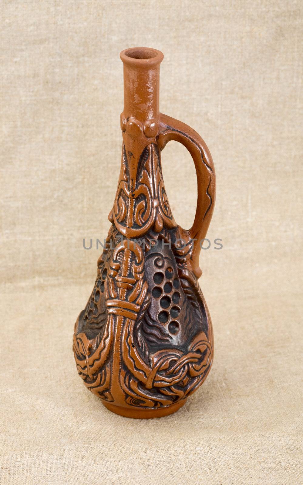 Ancient clay brown bottle on a textile background