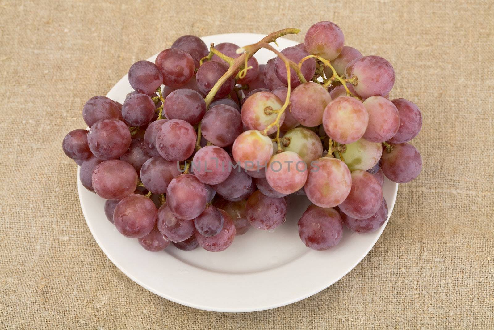 Red rip grapes on plate on the sacking background