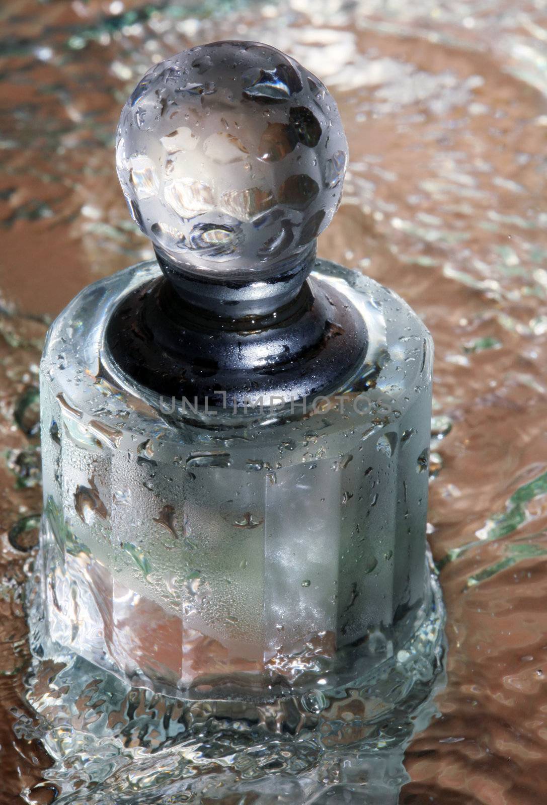 Glass bottle of perfumery in water with drops