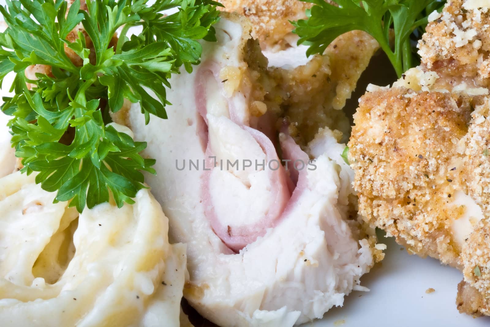 chicken cordon blue on a white plate breaded and close up