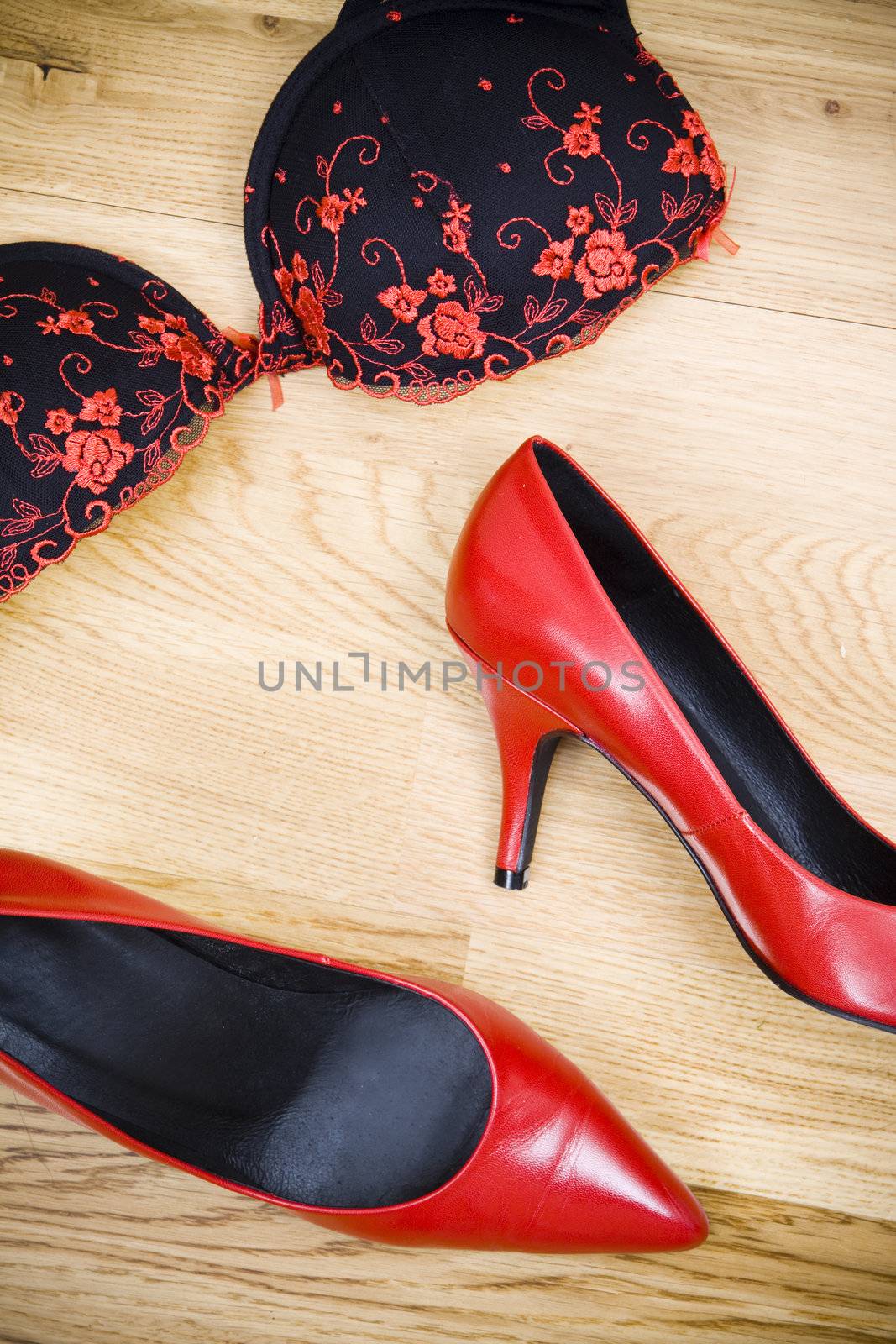 fashionable female shoes and bra on wooden floor