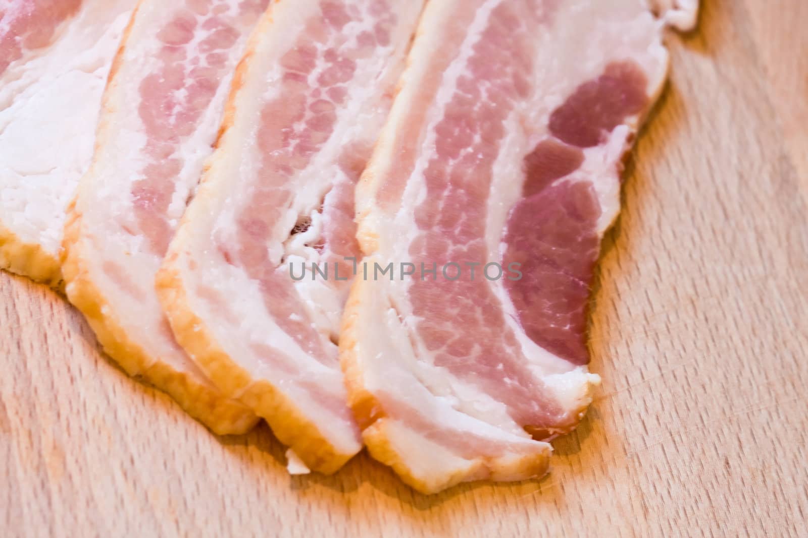 sliced raw bacon on a wood cutting board