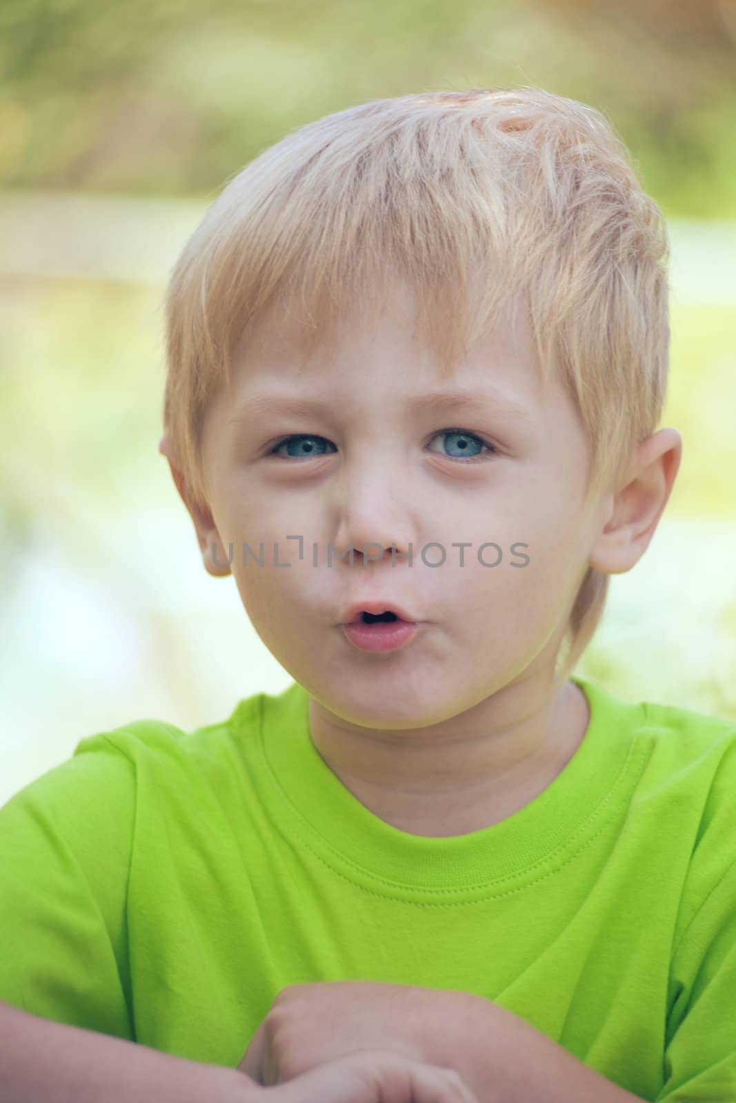 The little boy was talking enthusiastically. The age of three years. He looks straight into the camera. Background blur, solar lighting, shooting in nature