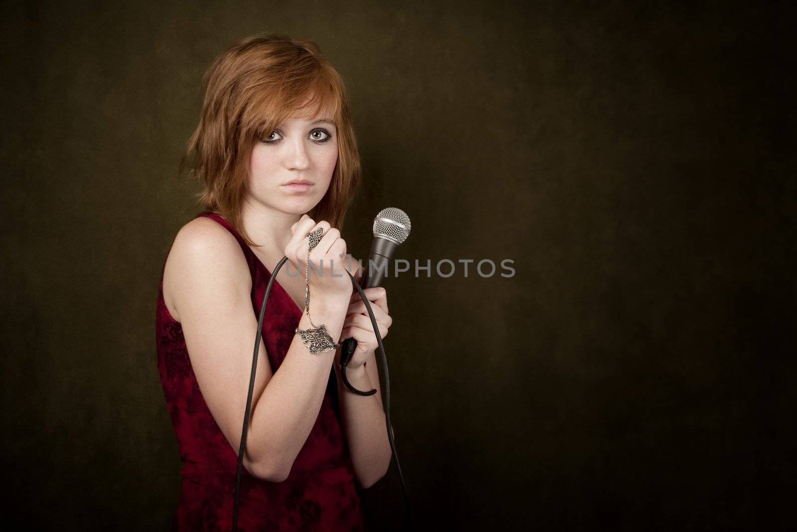 Pretty young girl with red hair on a green background with microphone
