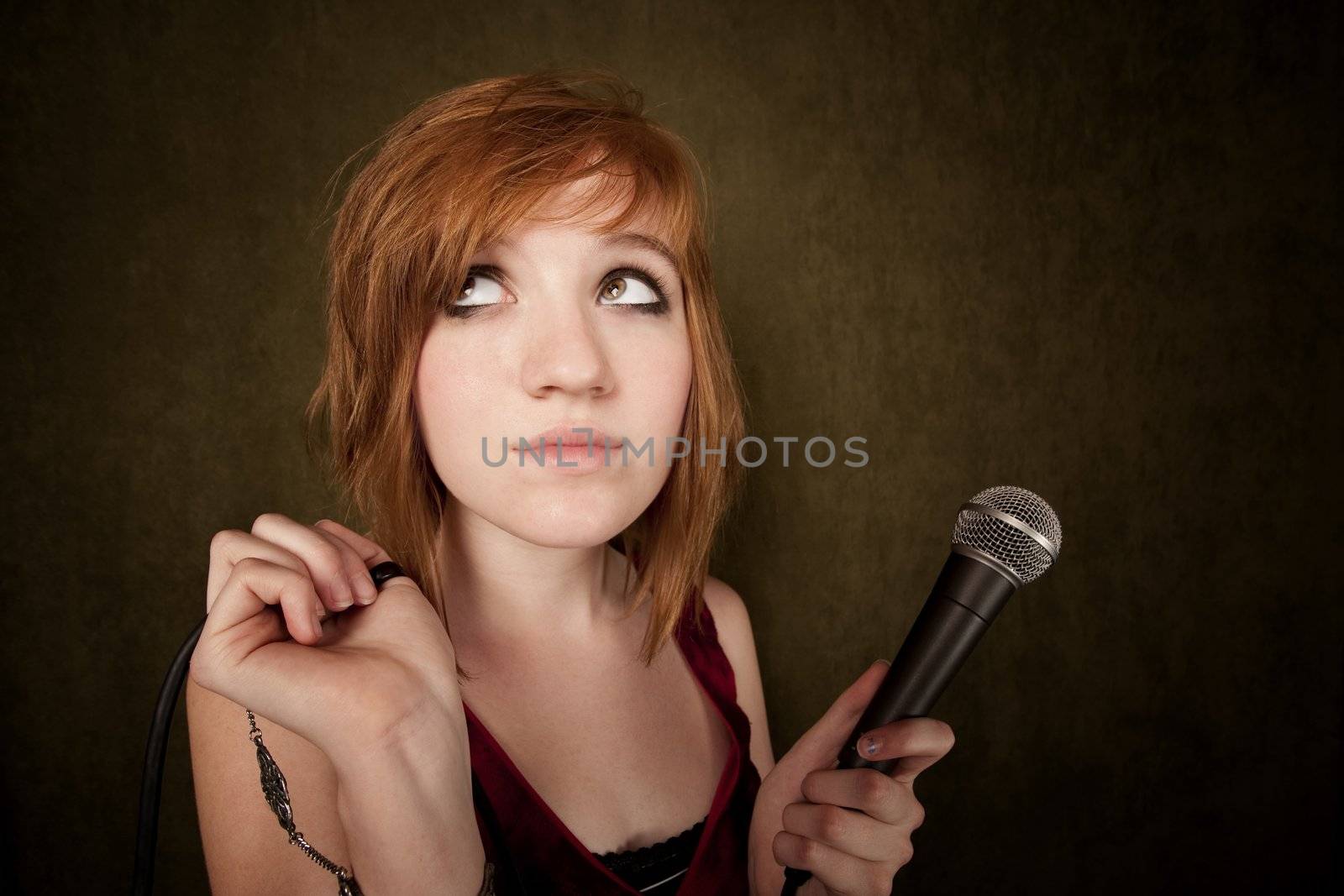 Pretty young girl with red hair on a green background with microphone