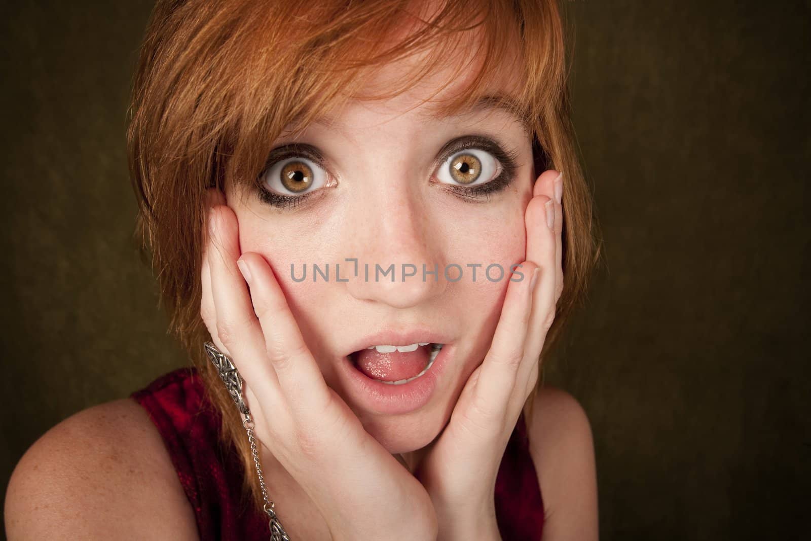 Shocked pretty young girl with red hair on a green background