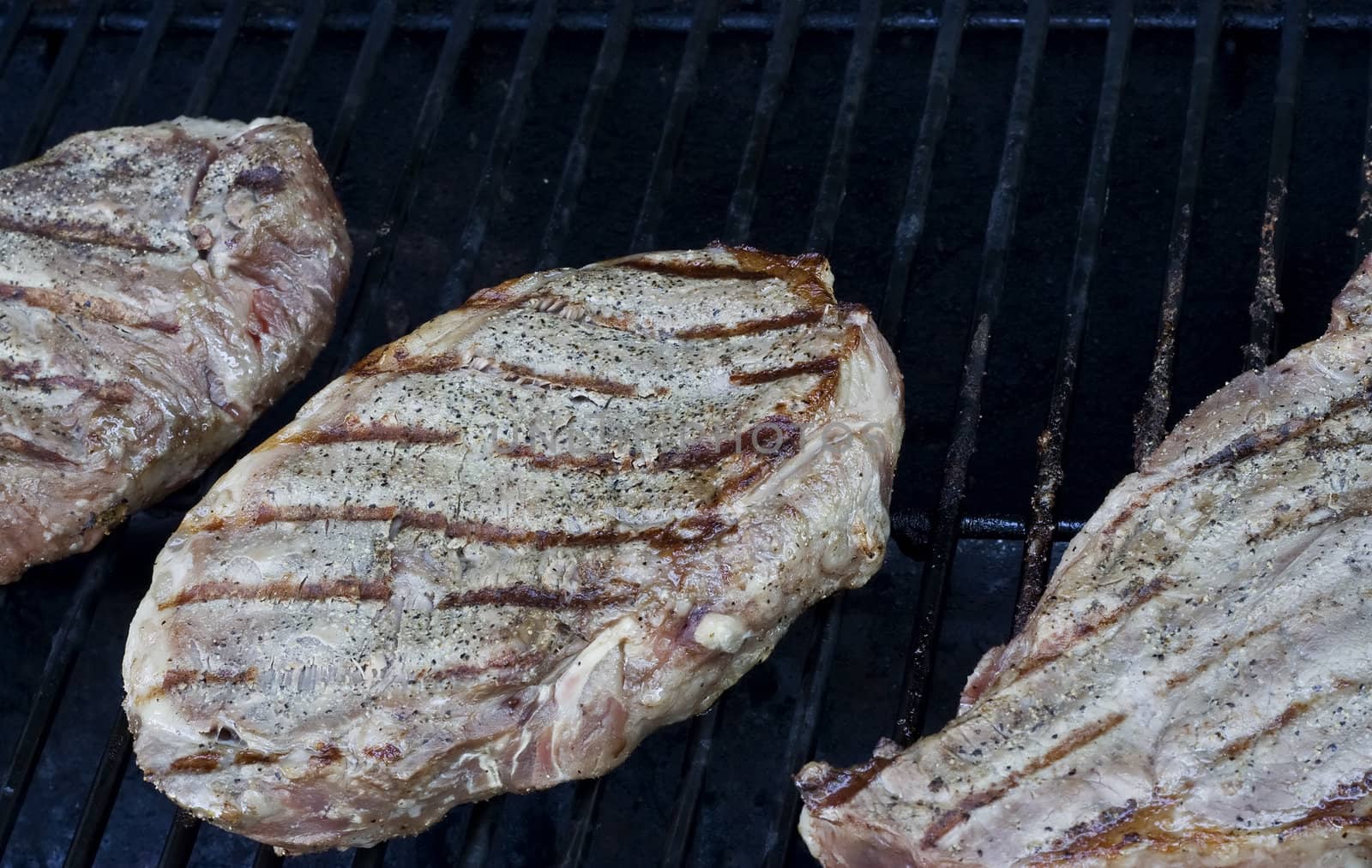 Grilling steaks on the grill nice cuts of meat close up shot shallow DOF