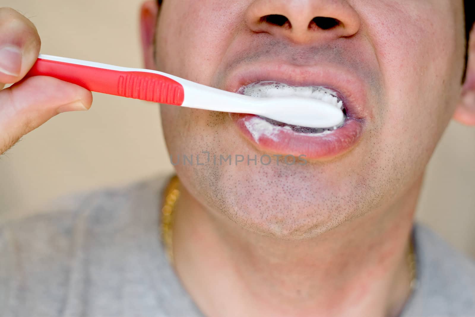 A closeup of a young man while he is brushing his teeth.
