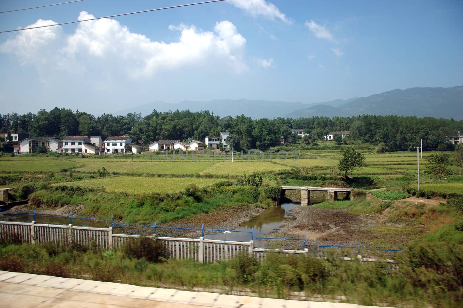 Chinese village in Hunan province. General landscape with river, rice fields, hills and trees.