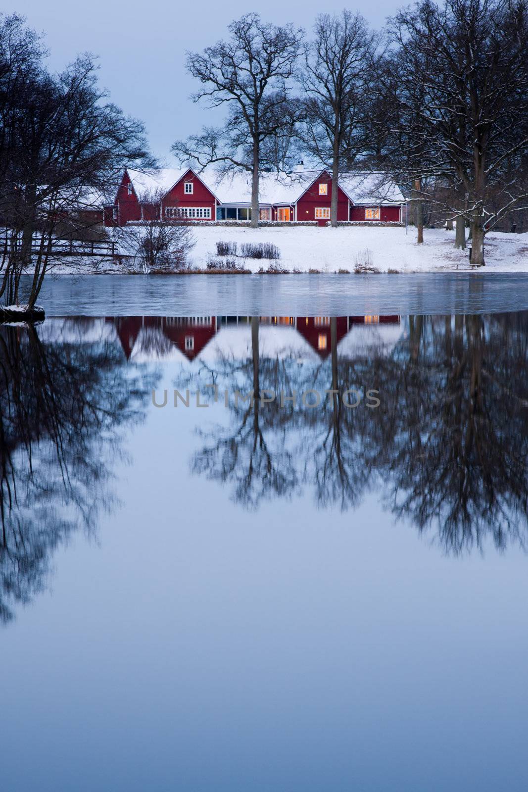 Red home a dawn near a lake with its reflection.