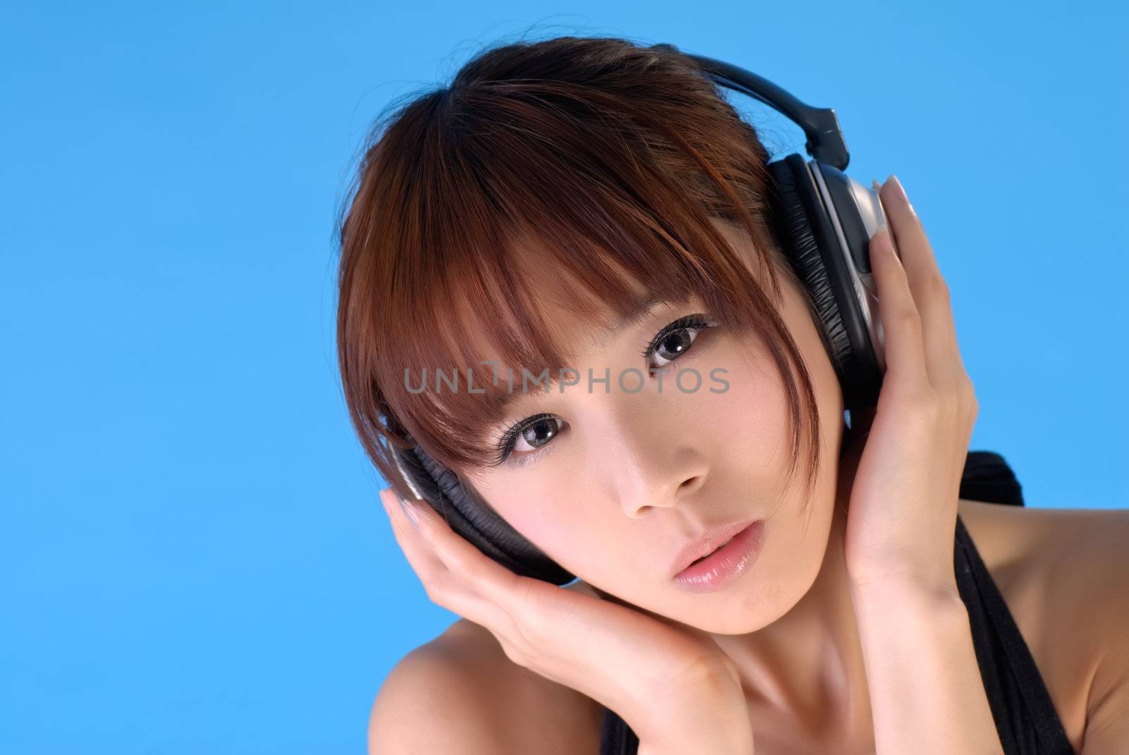 Asian beauty with headphone, closeup portrait on blue background.