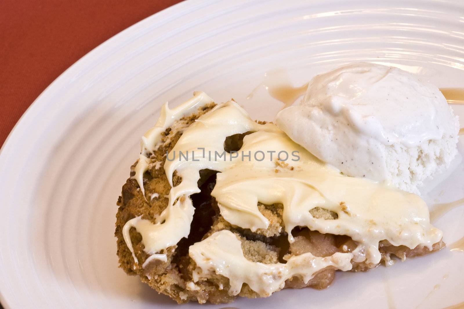 slice of apple pie frosted with vanilla ice cream on white plate