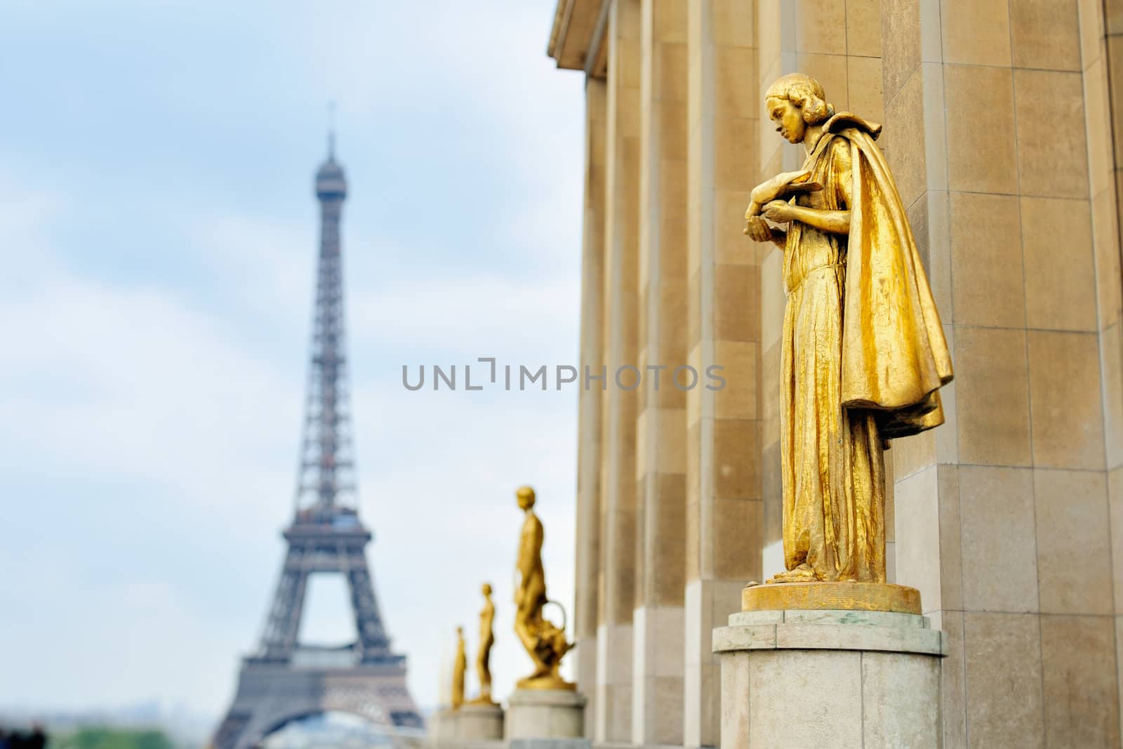 Golden statues and Eiffel tower on square in Paris