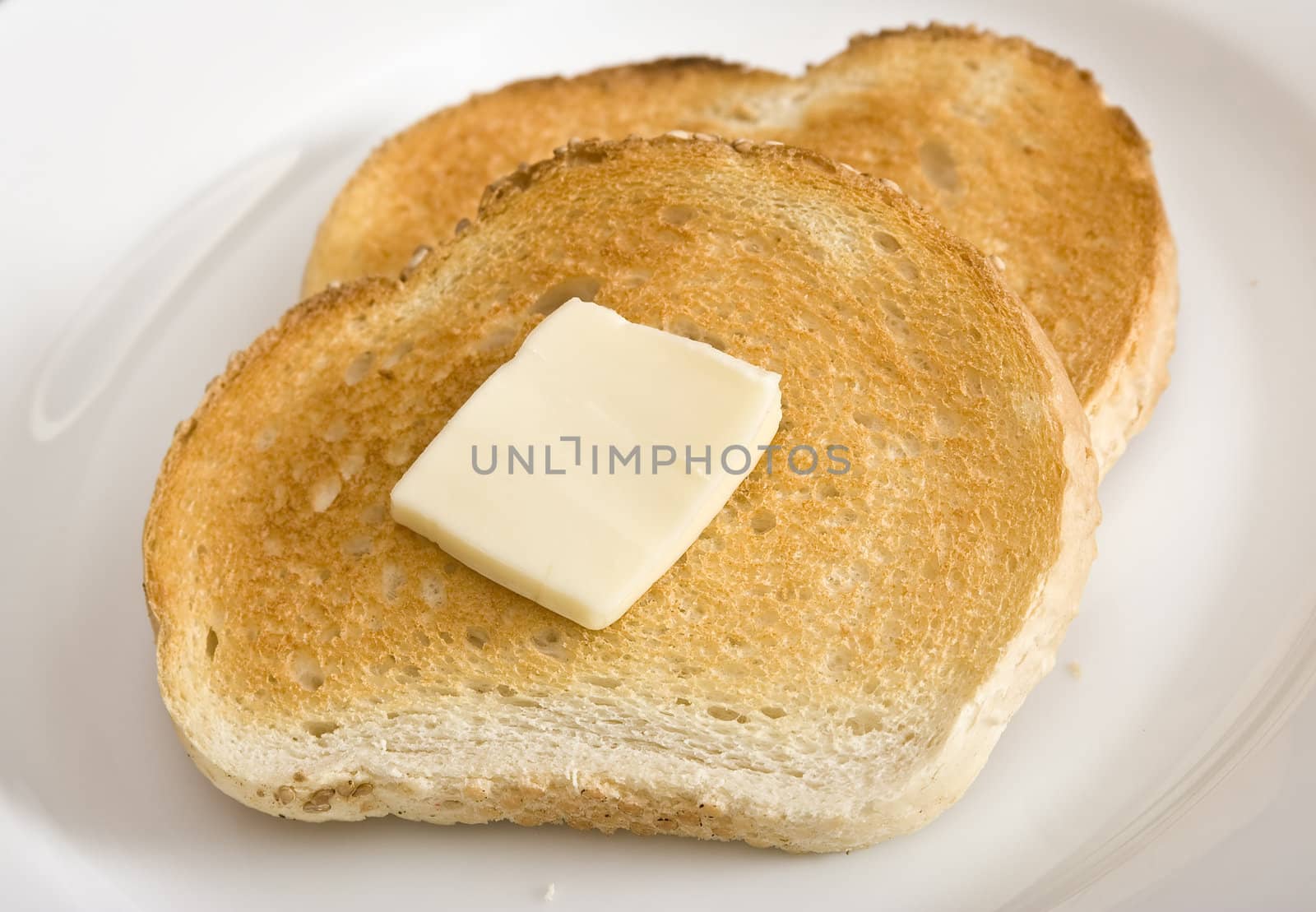 Two sllices of toast and a slice of butter on a white plate