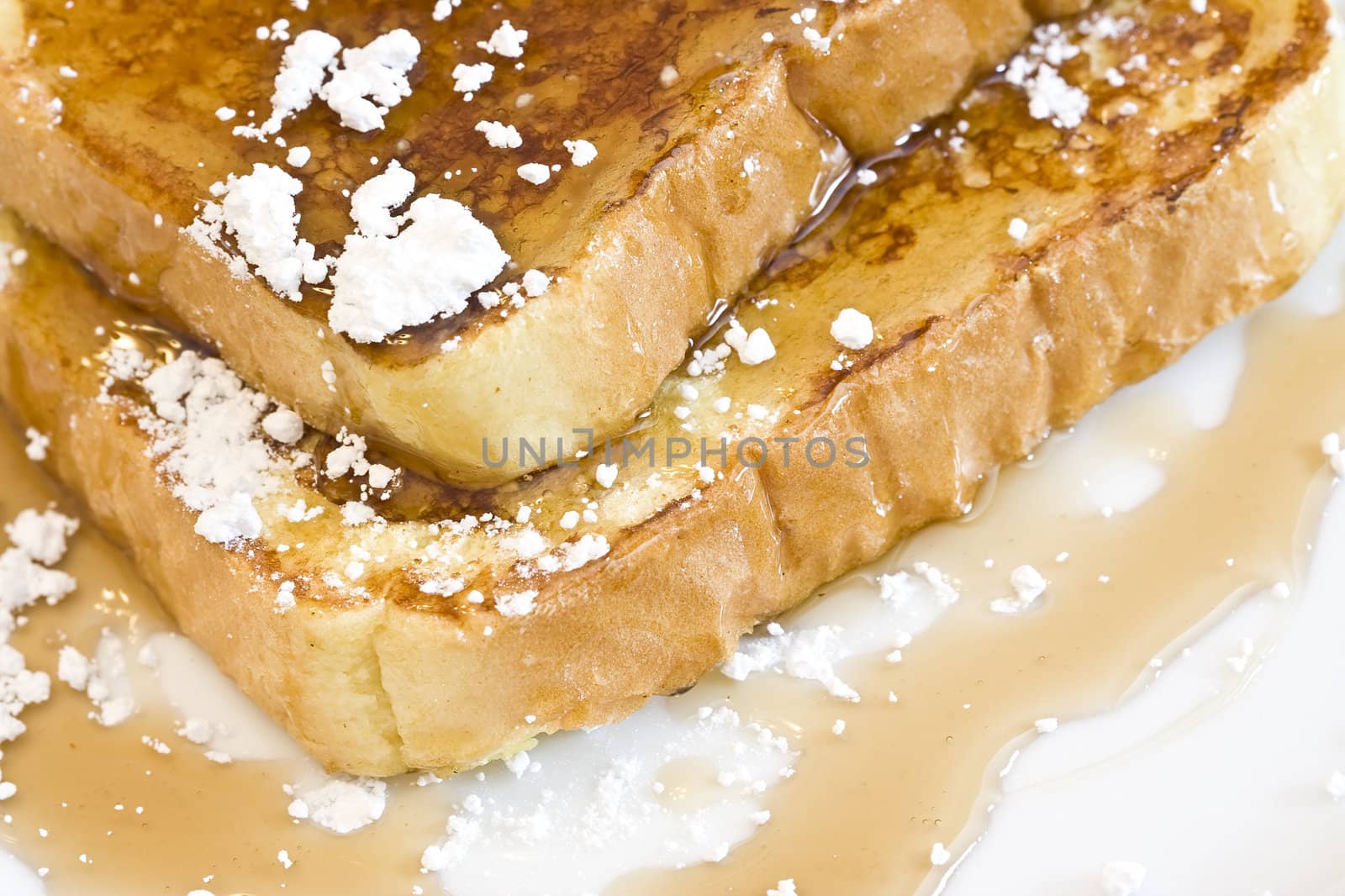 french toast on a white plate with powdered sugar and maple syrup 