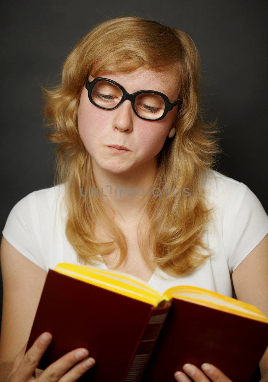 Young woman in a funny old-fashioned glasses reading a book