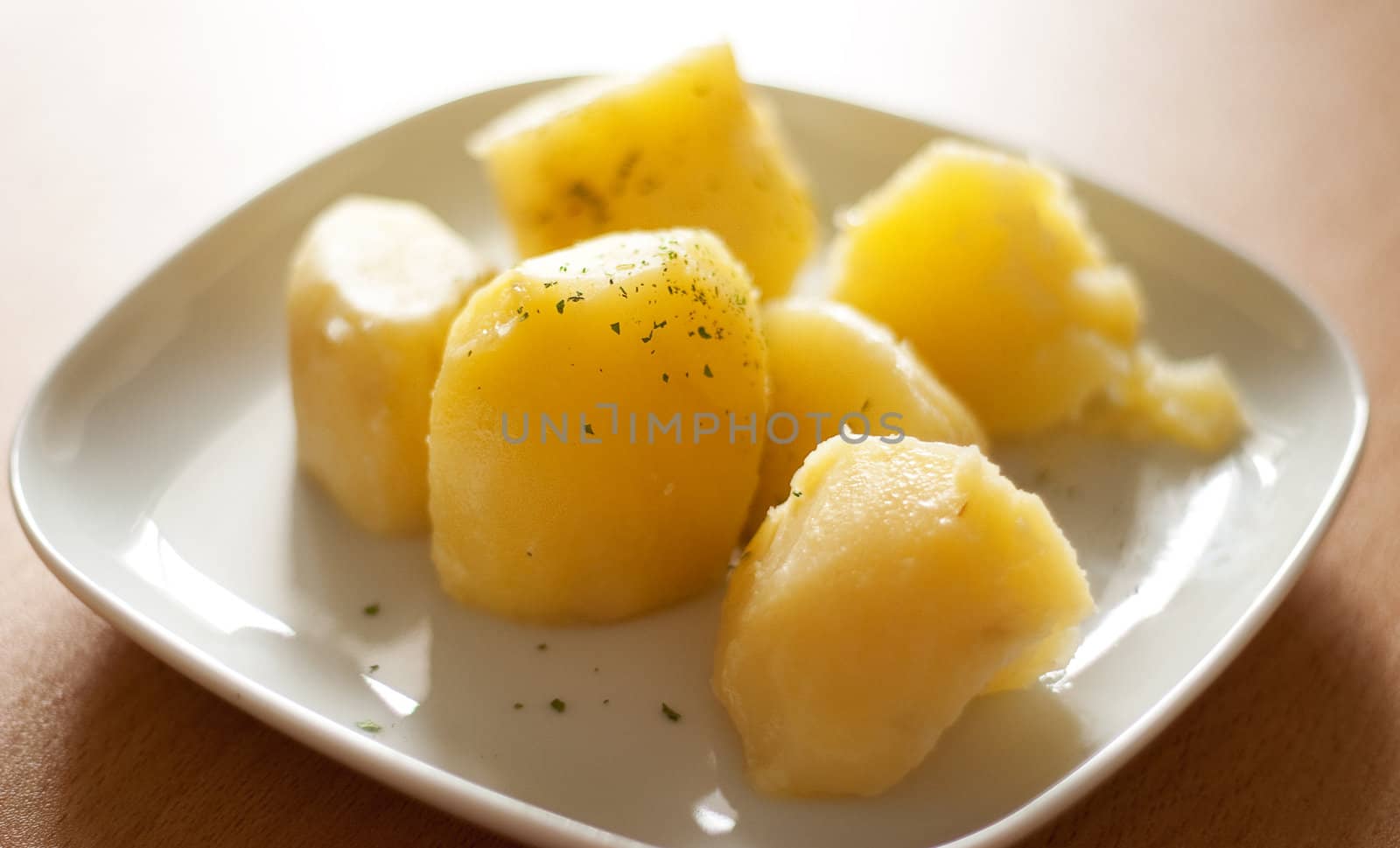 Boiled potatoes and greens on a plate. The back light.