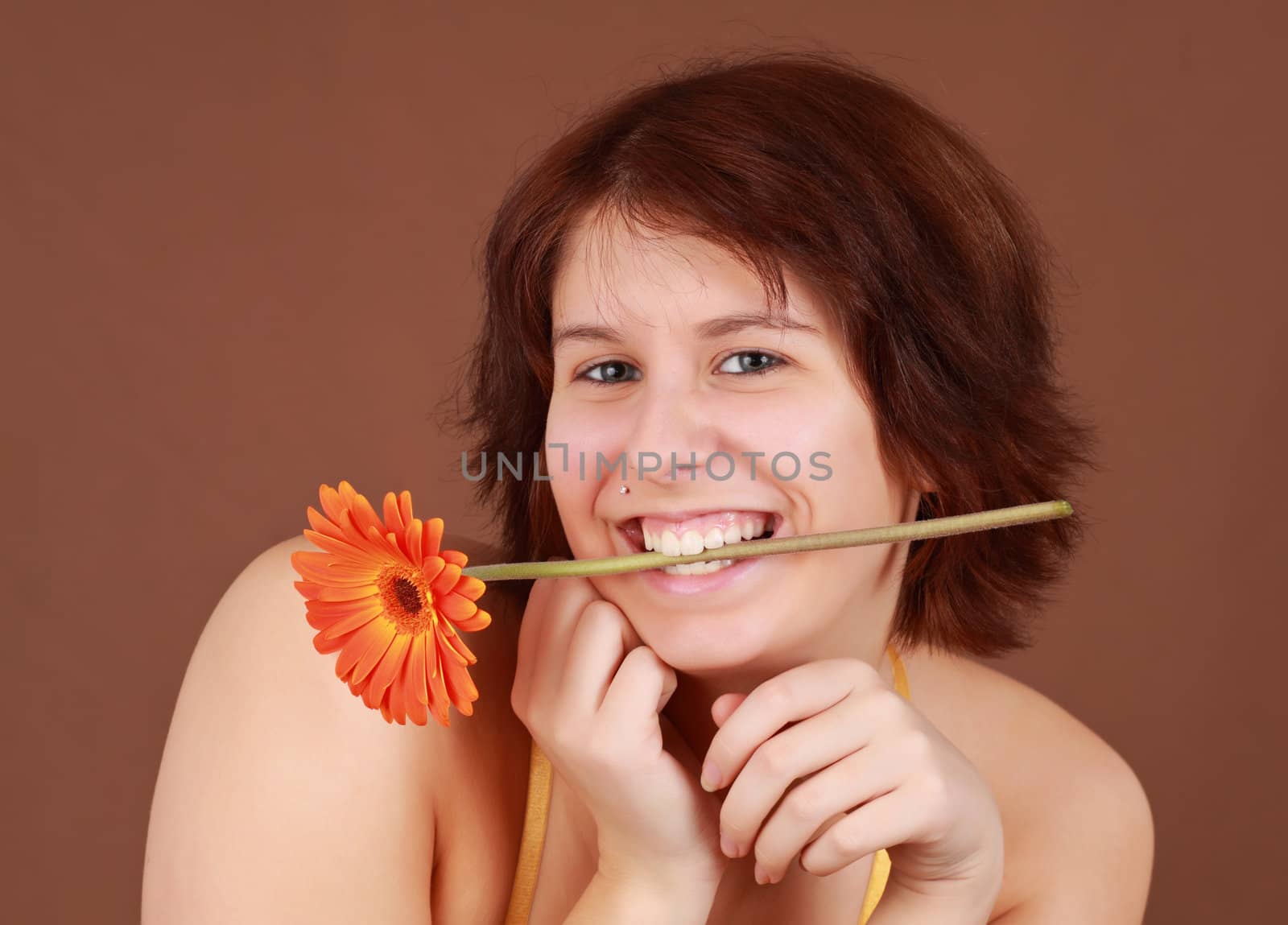 girl holding a natural gerber flower with her teeth