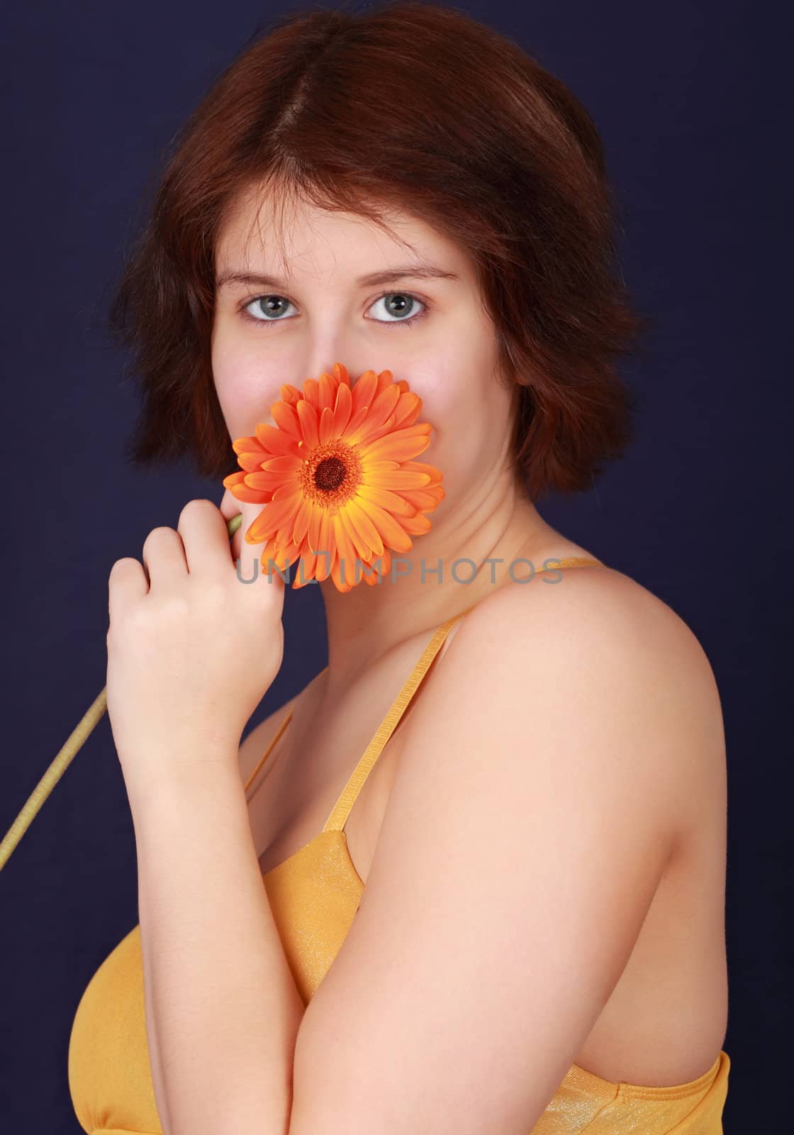 young caucasian woman hiding her mouth behind a flower