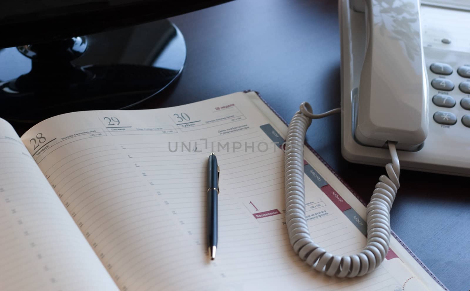 Personal workplace: table, monitor, business is a diary and telephone. Conception of office work.