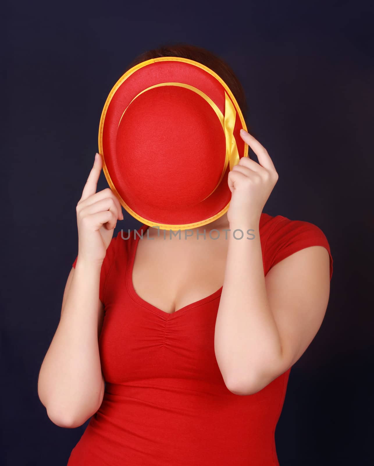 woman in red, hiding behind hat, black background