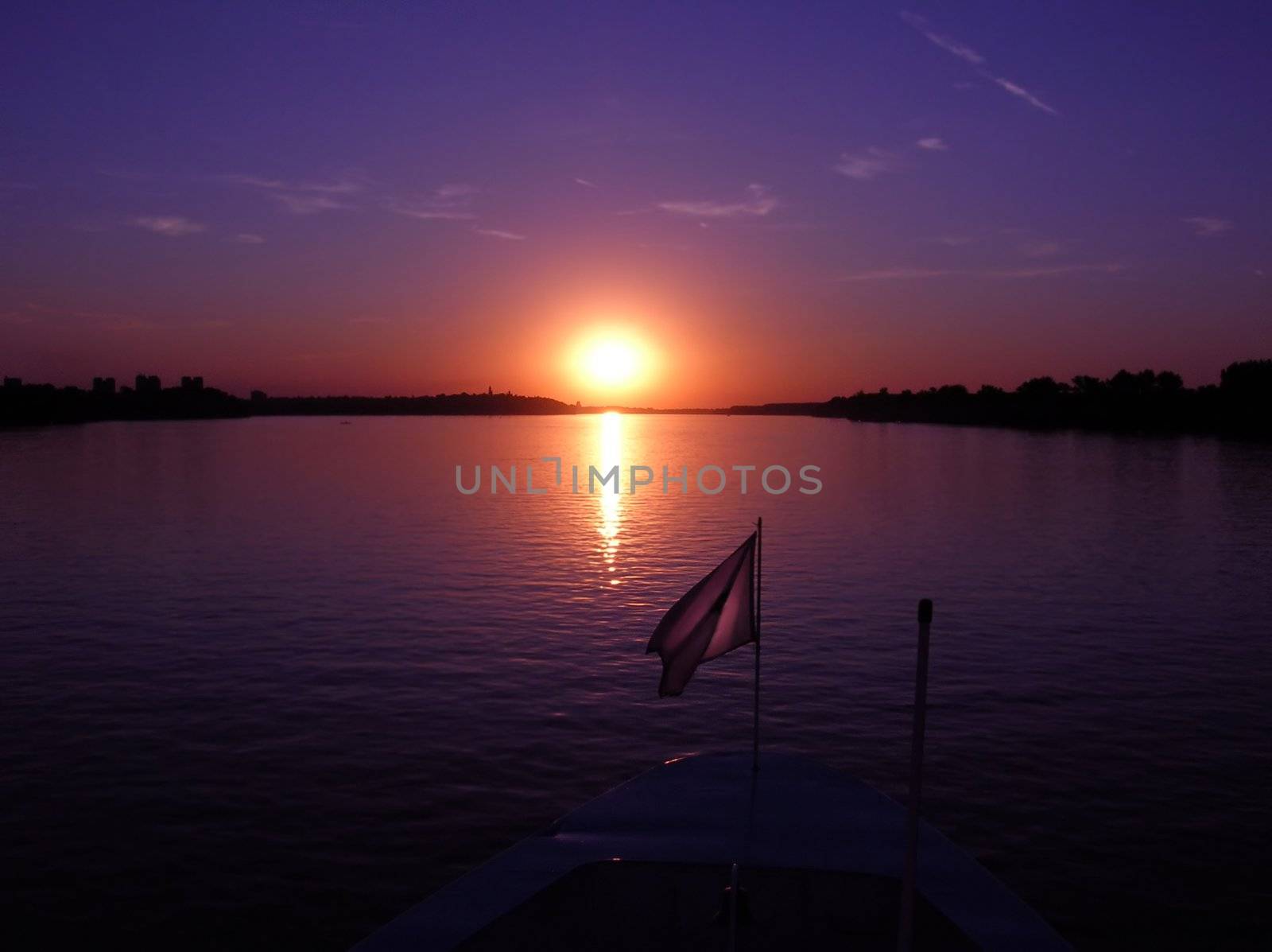 purple sunset over dark river from boat
