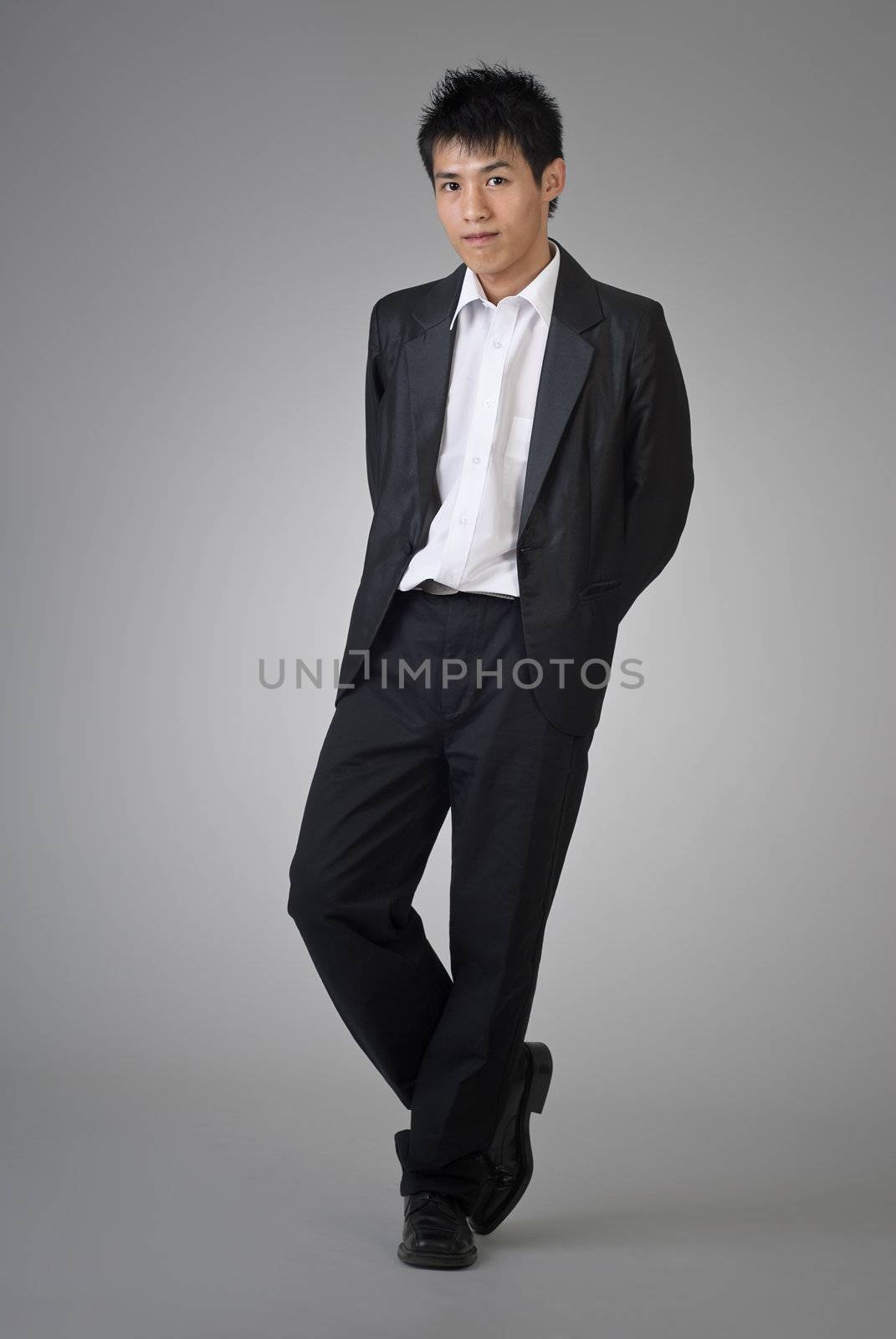 Attractive Asian business man posing on studio gray background.