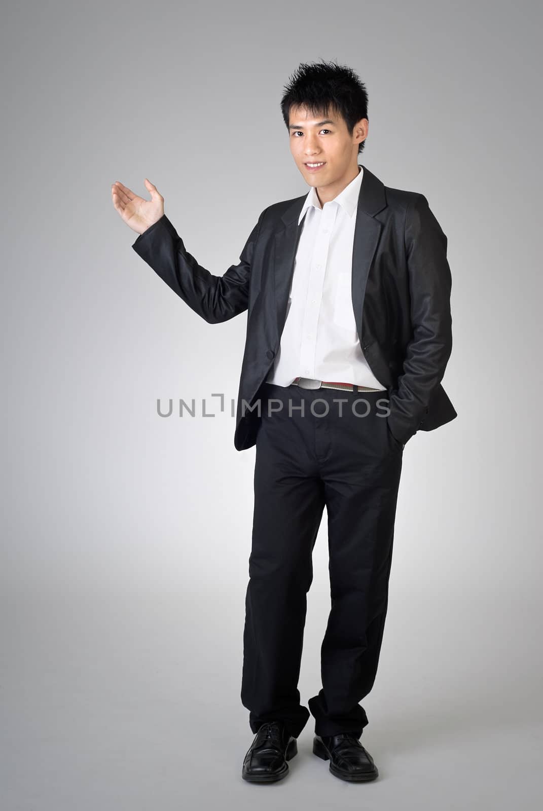 Young business man introduced over studio gray background.