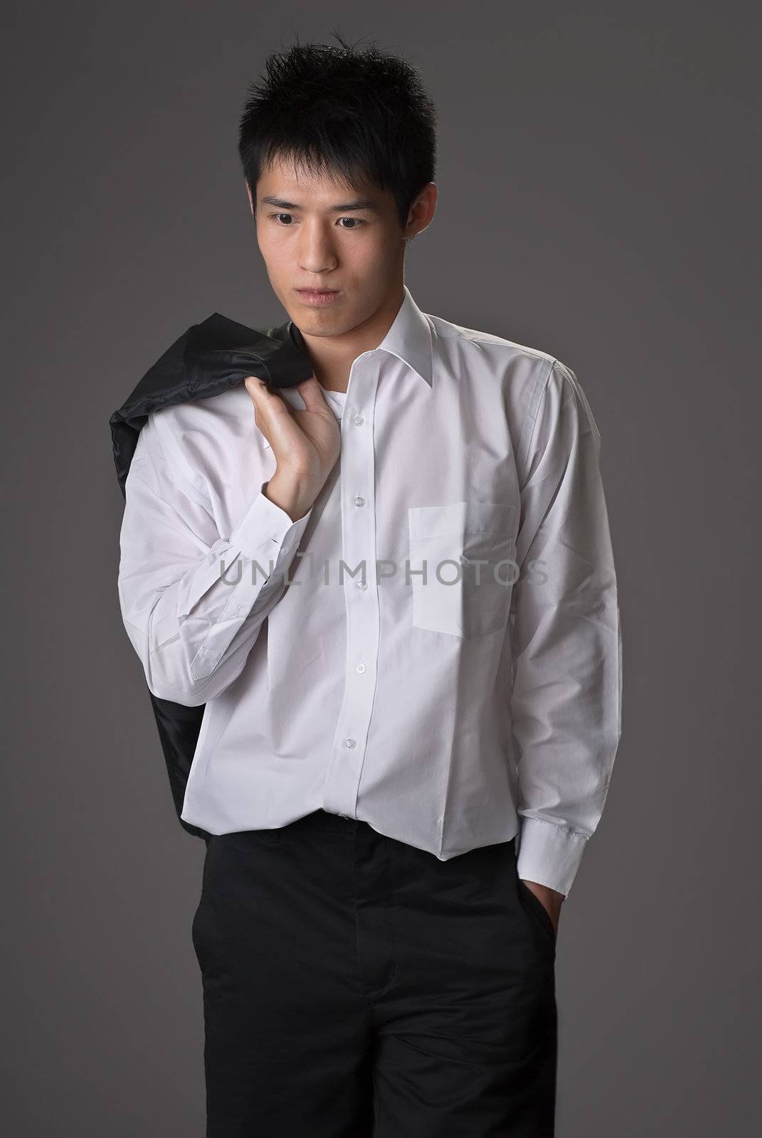 Lonely young man of business put coat on shoulder over studio gray background.