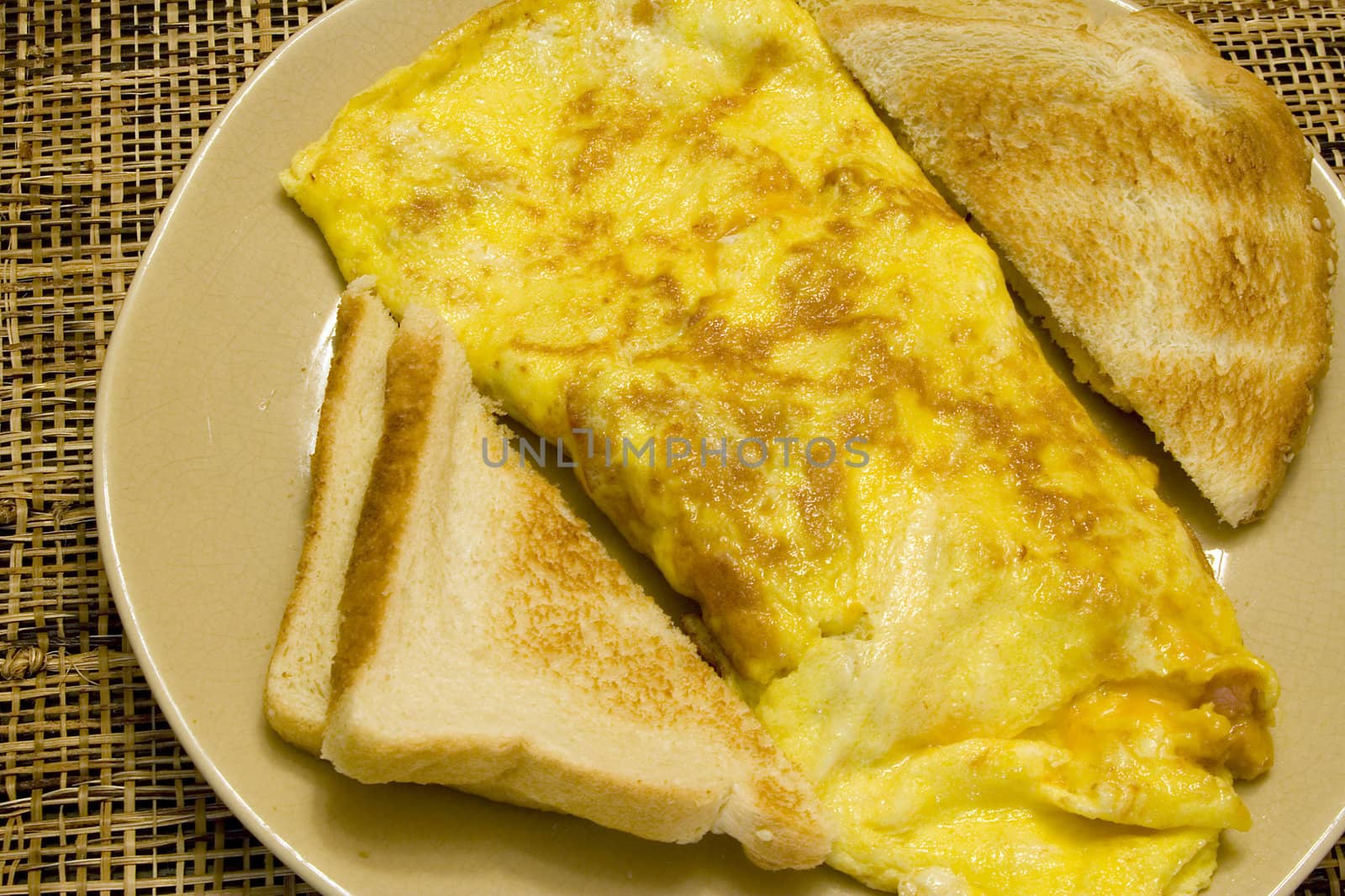 Omelette and white toast on a tan plate on a wicker placemat