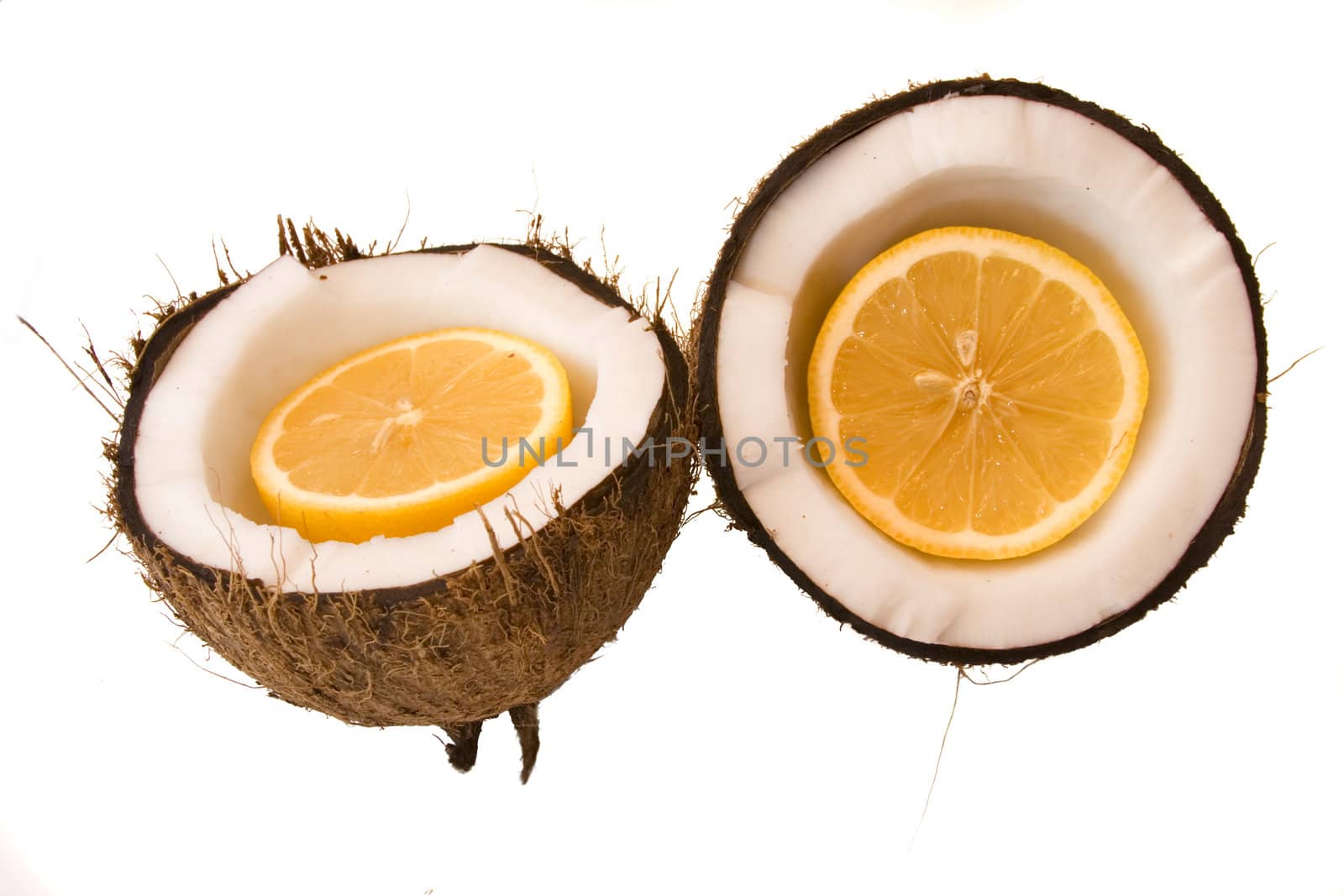 a coconut split in half with a orange cut in half in the cavity isolated on white background