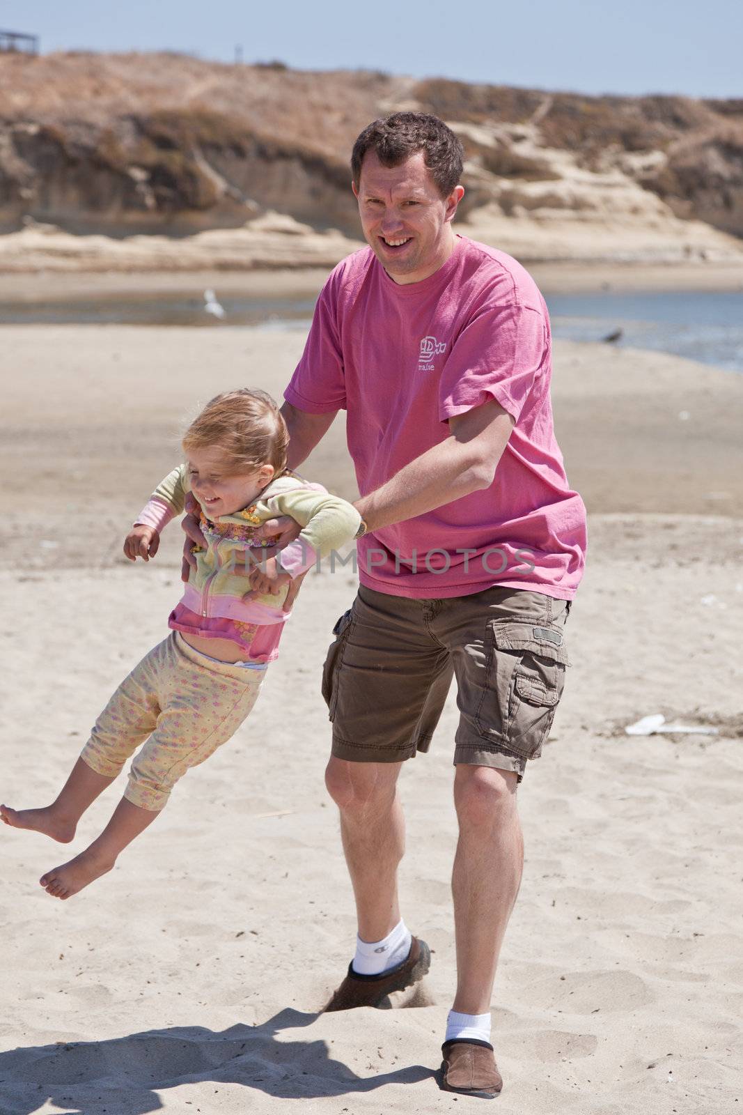 Father having fun with his daughter on the beach.
