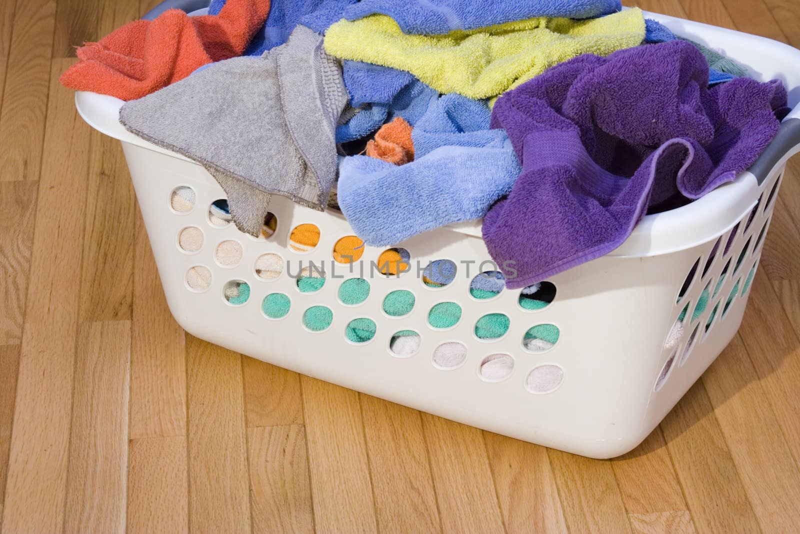 laundry basket full of clean towels on hardwood floor