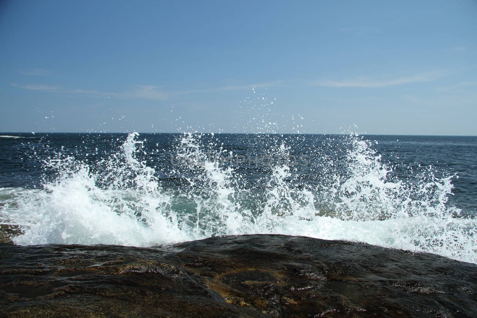 Water splashing against coastal rocks on a sunny day