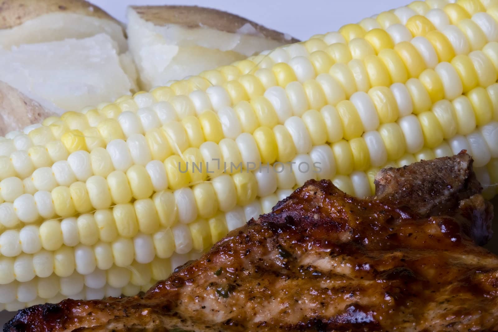 country style dinner corn on the cob on a white plate with a red checkered place mat