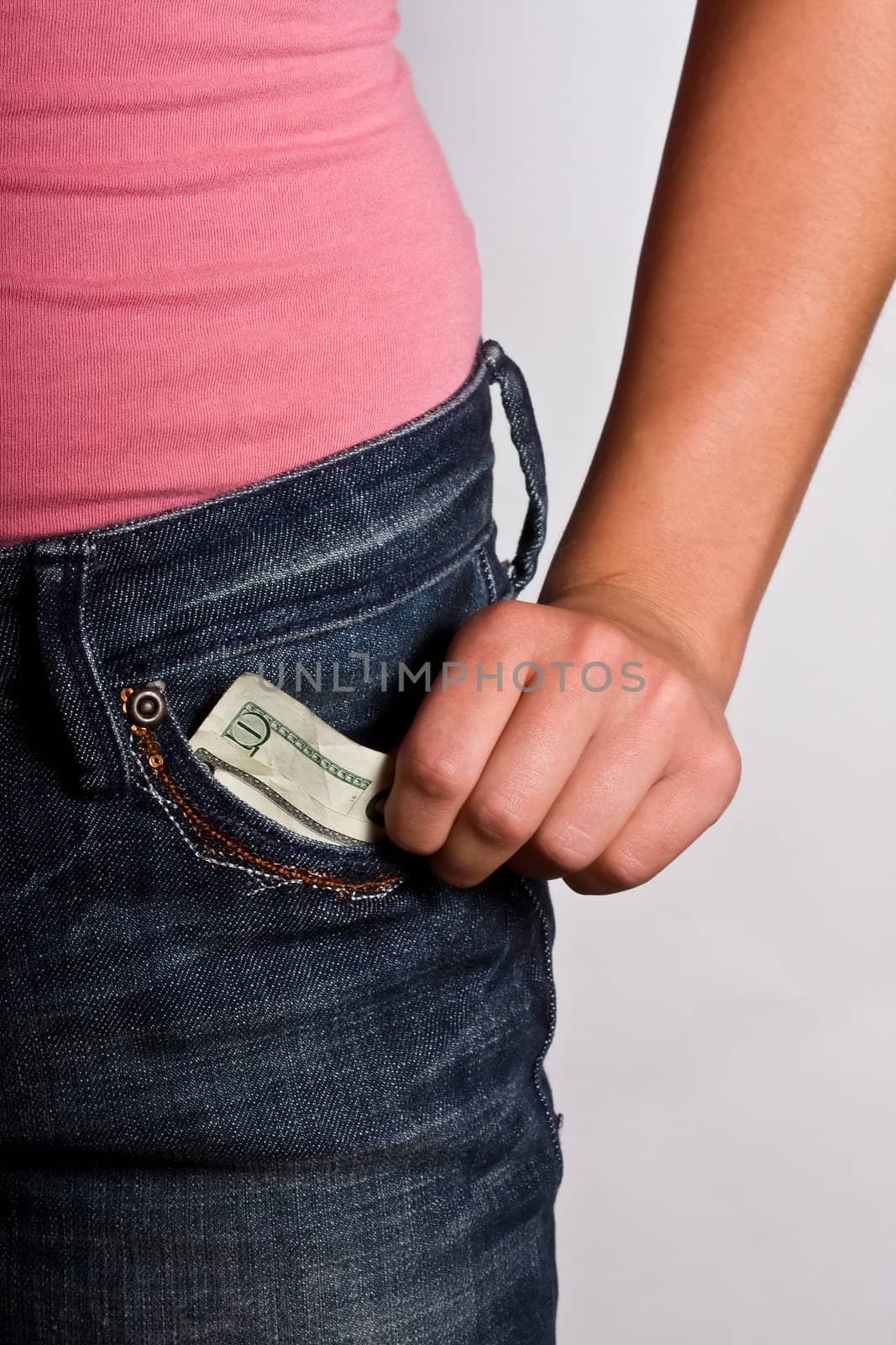 teen girl with money to burn blue jeans and pink shirt stuffing money in front pocket