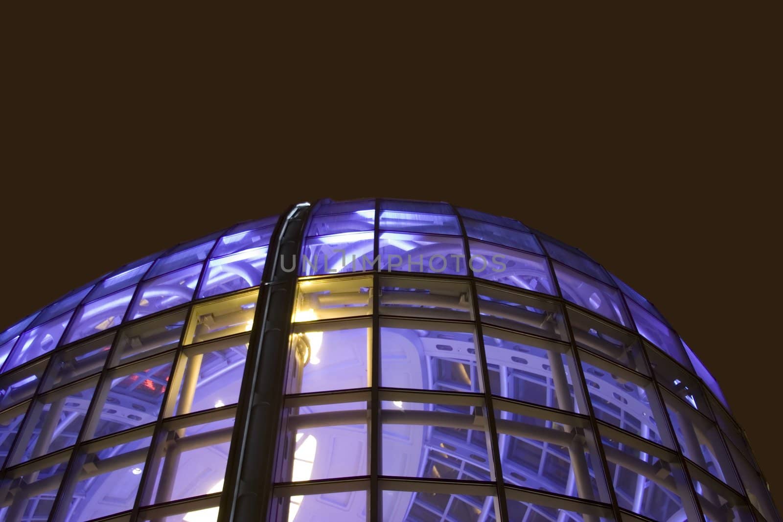 Night shot of glass office building window glass lit with blue purple light room for type above building