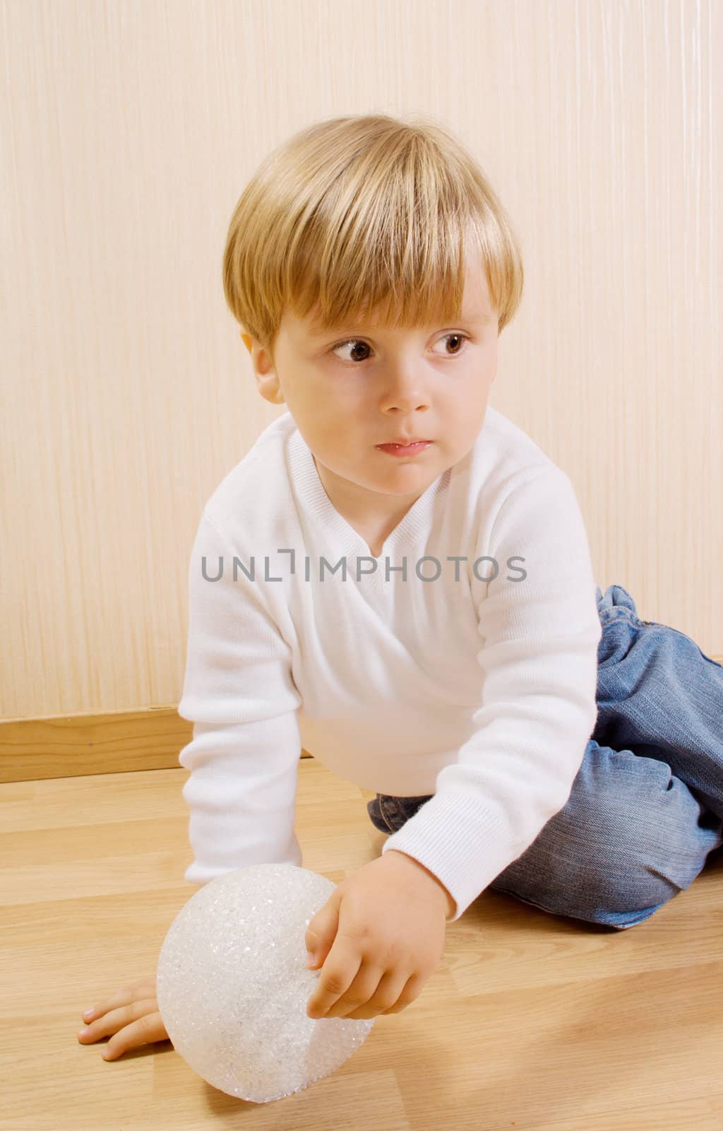 The child on the wood floor with white ball