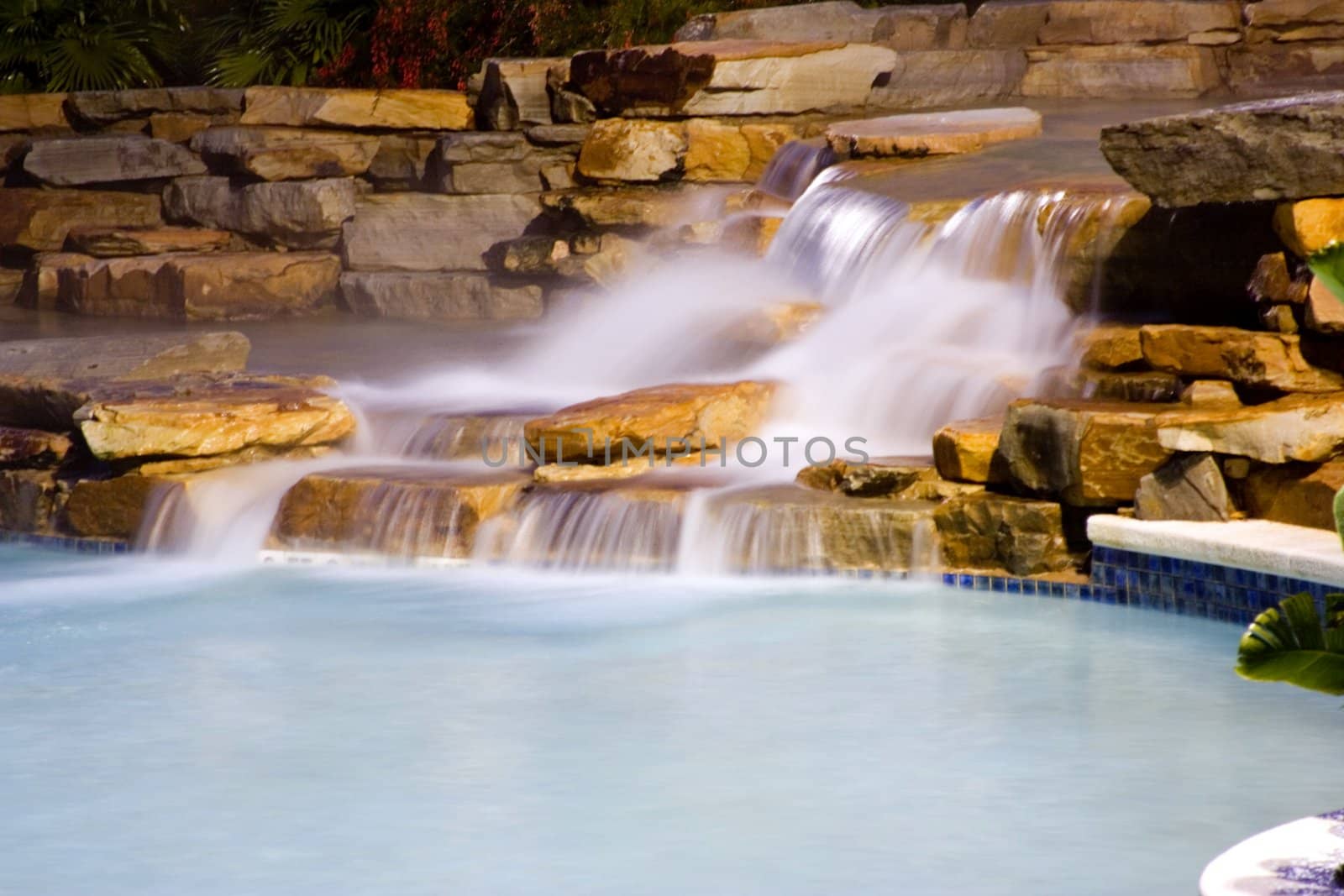 long exposure of water falls entering a rocky vacation resort pool at night