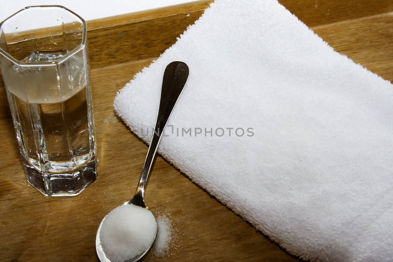 spoon of salt and glass of water on towel and wood serving tray for home healing