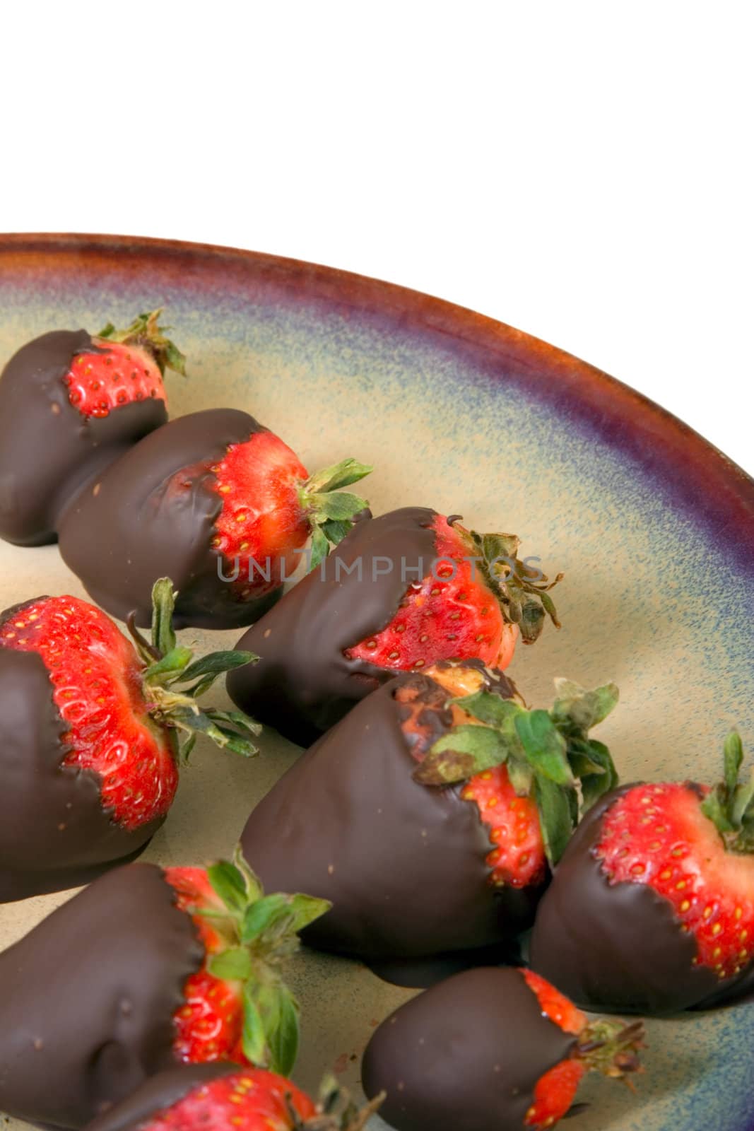 Chocolate covered strawberries on ceramic brown plate on white background