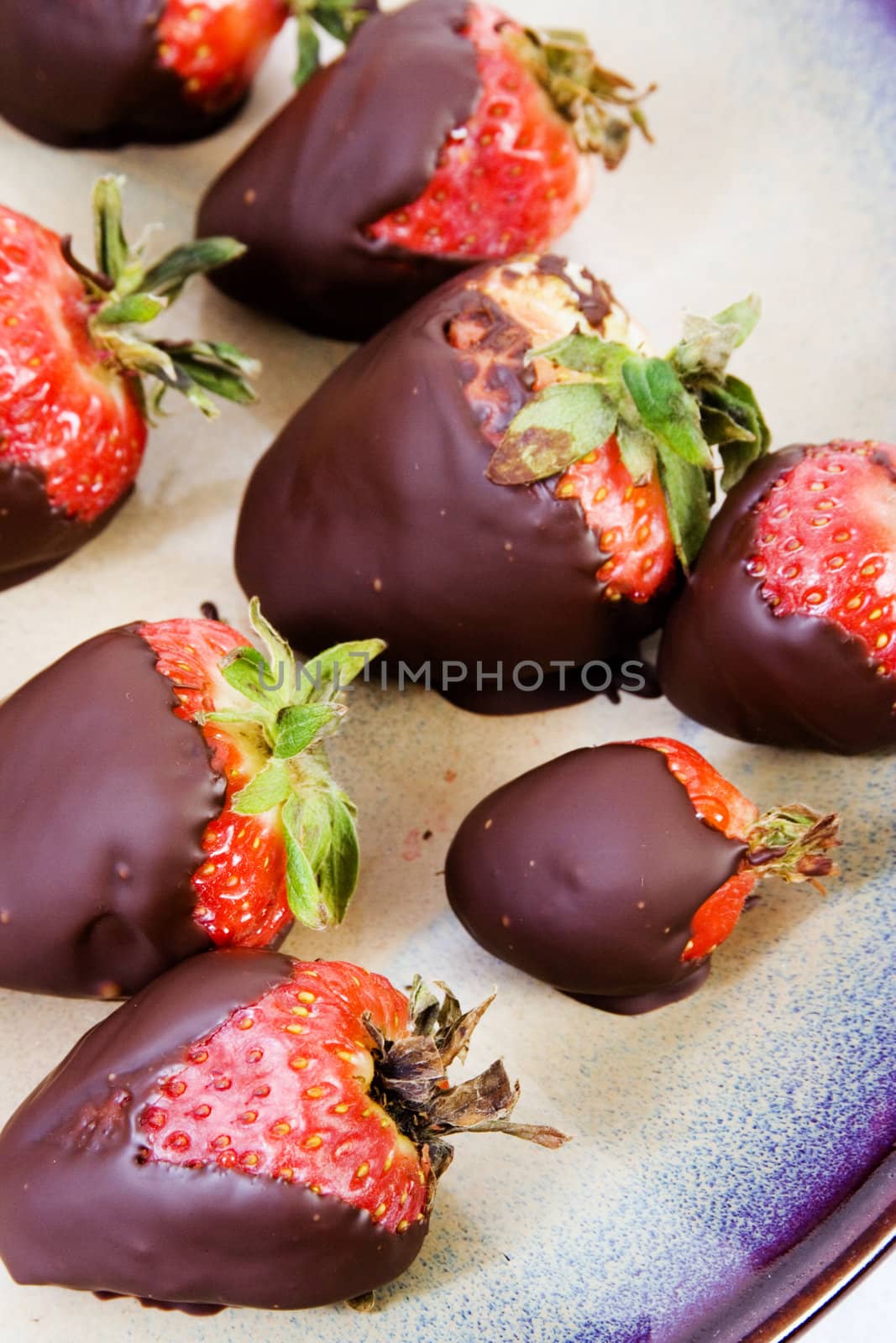 Chocolate covered strawberries on ceramic brown plate on white background