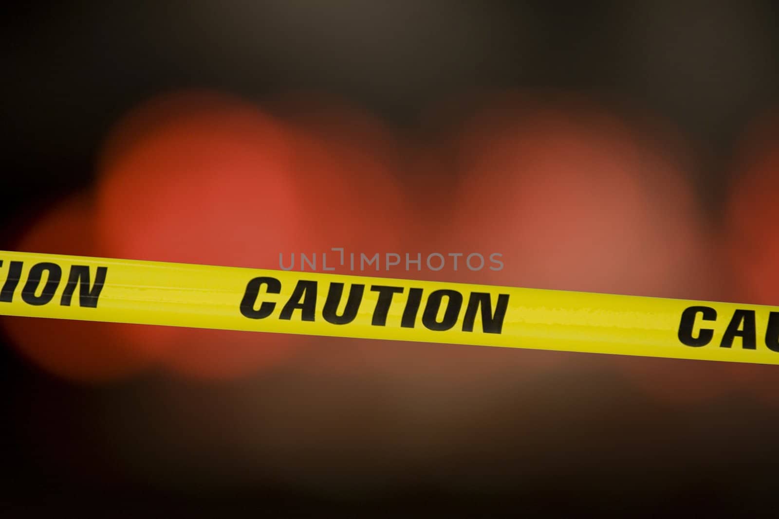 Caution tape over a black background with flashing lights in the background