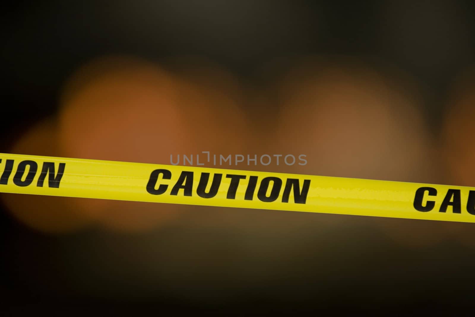 Caution tape over a black background with flashing lights in the background