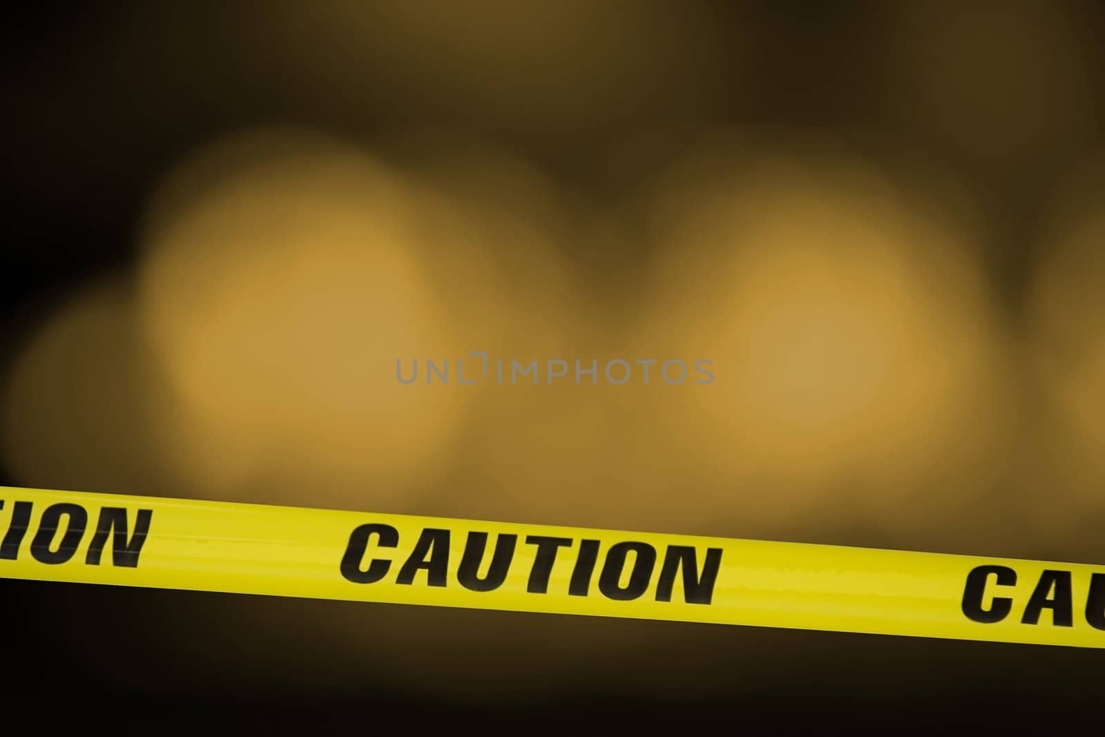Yellow tape with the word caution on it across a warning light background