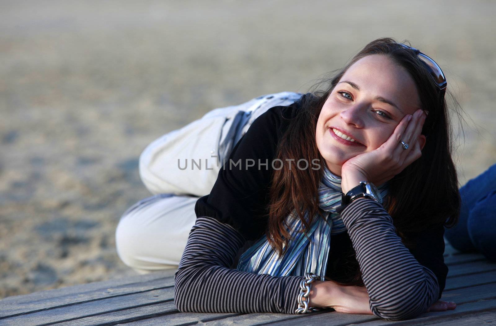 The laughing brunette sits on the wooden bridge at beach