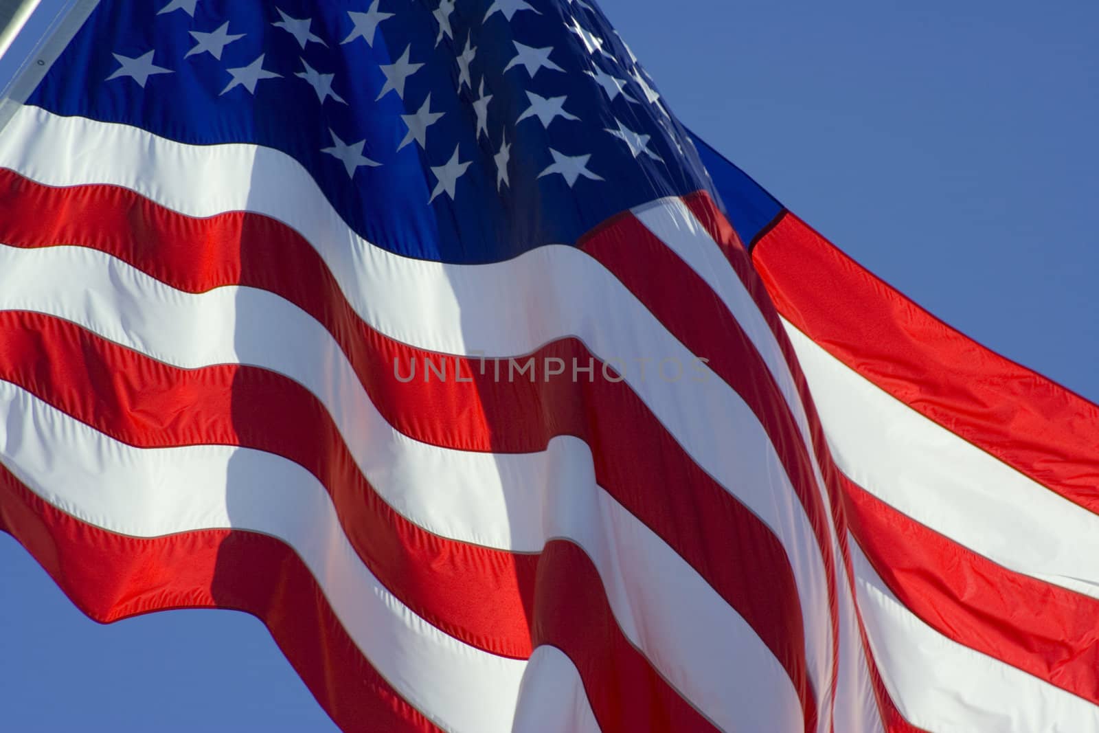 Tilted stars and stripes flying in the wind on deep blue sky nice background for a patriotic display